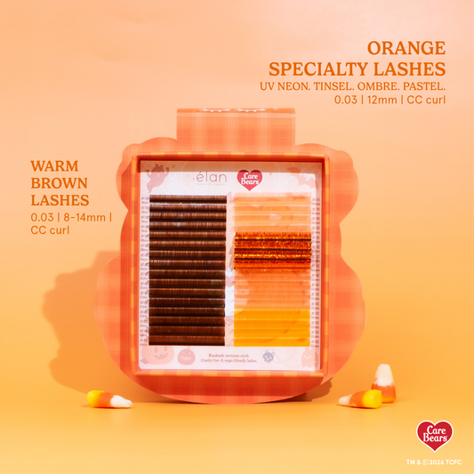 Élan Beauté x Care Bears Halloween lash tray featuring warm brown lashes and orange specialty lashes in UV neon, tinsel, ombré, and pastel styles, displayed in orange seasonal packaging with candy corn around it.