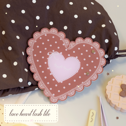 Lace Heart Lash Tile in brown with pink polka dots laying on a brown bag with tweezers and a waffle mirror surrounding it. 
