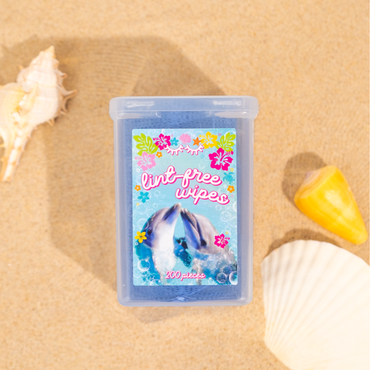 Lint-free wipes, 200-count, in tropical dolphin-themed packaging displayed on beach sand beside seashells.