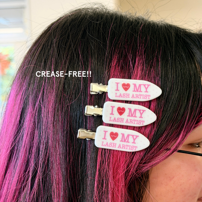 Person wearing crease-free hair clips with white and pink polka dots and text on it saying "I Heart My Lash Artist" in pink text.