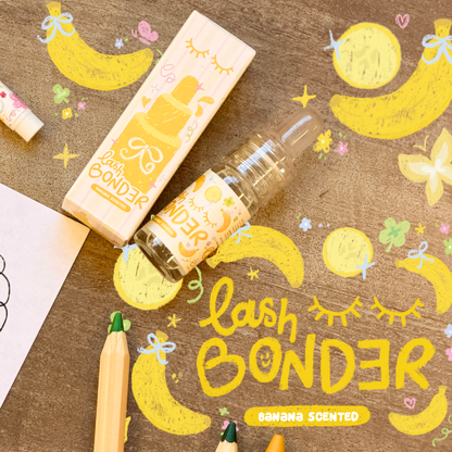 Banana-scented lash bonder beside its yellow and white packaging and drawings of bananas, butterflies, and colored pencils.