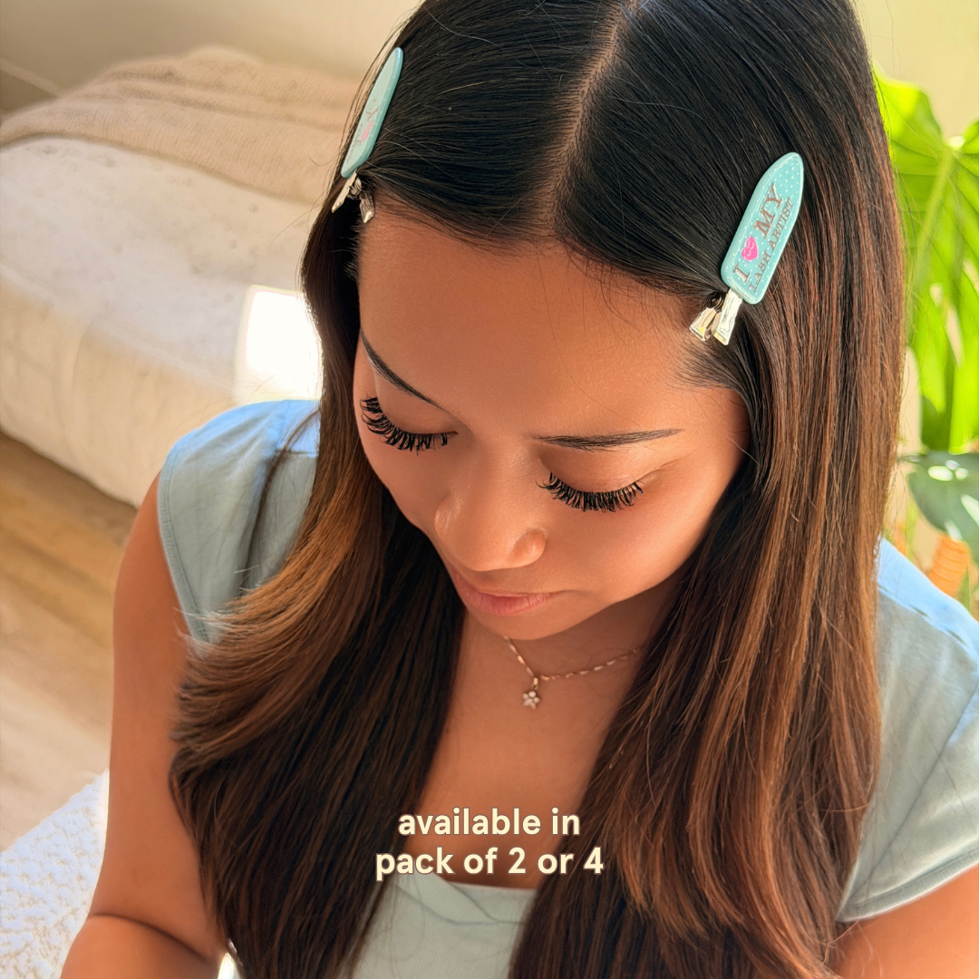 Lash client wearing two sky blue “I Love My Lash Artist” hair clips, shown with long eyelash extensions; available in packs of 2 or 4.