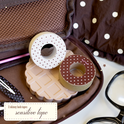 2 skinny lash tapes Sensitive Tape with brown with white polka dots on the side and white with brown polka dots on the other. Laying on a brown bag with hair clips and glasses on the side.