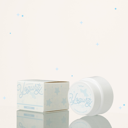 Side view of unscented yogurty lash remover beside its blue-and-white packaging.