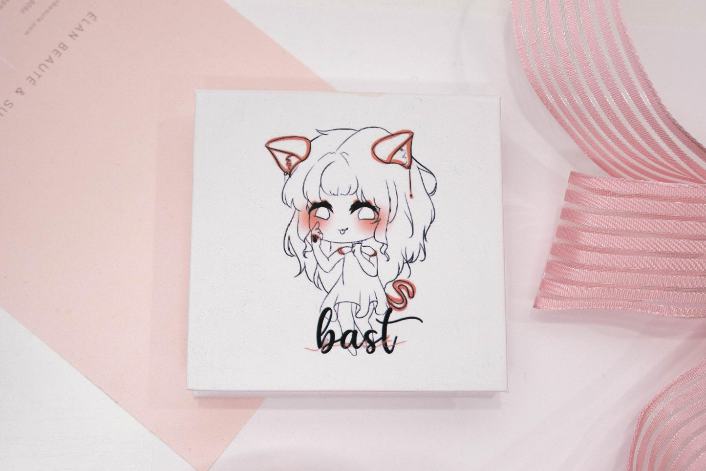 Bast false eyelash box featuring an illustrated character on a white and pale pink background.