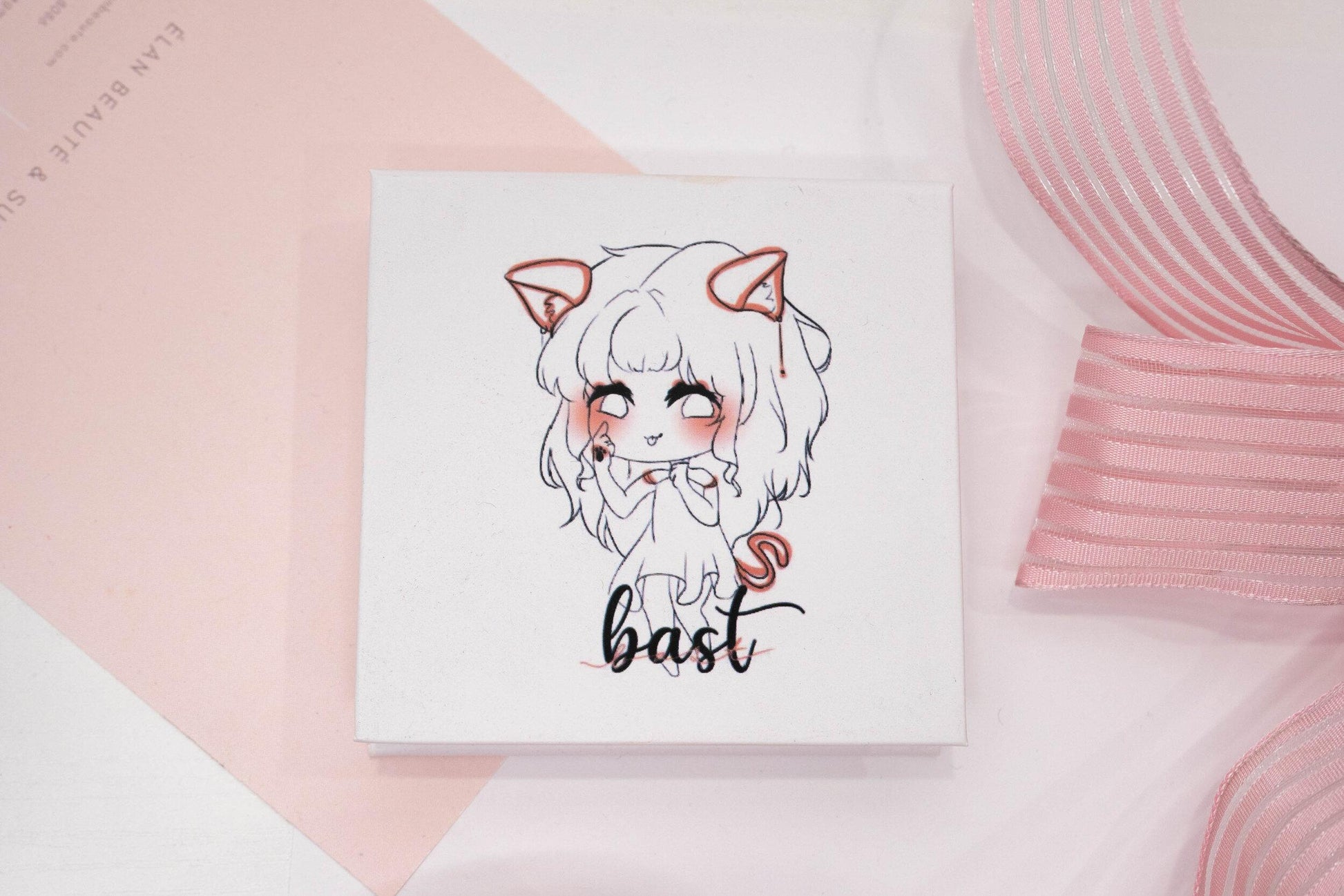 Bast false eyelash box featuring an illustrated character on a white and pale pink background.