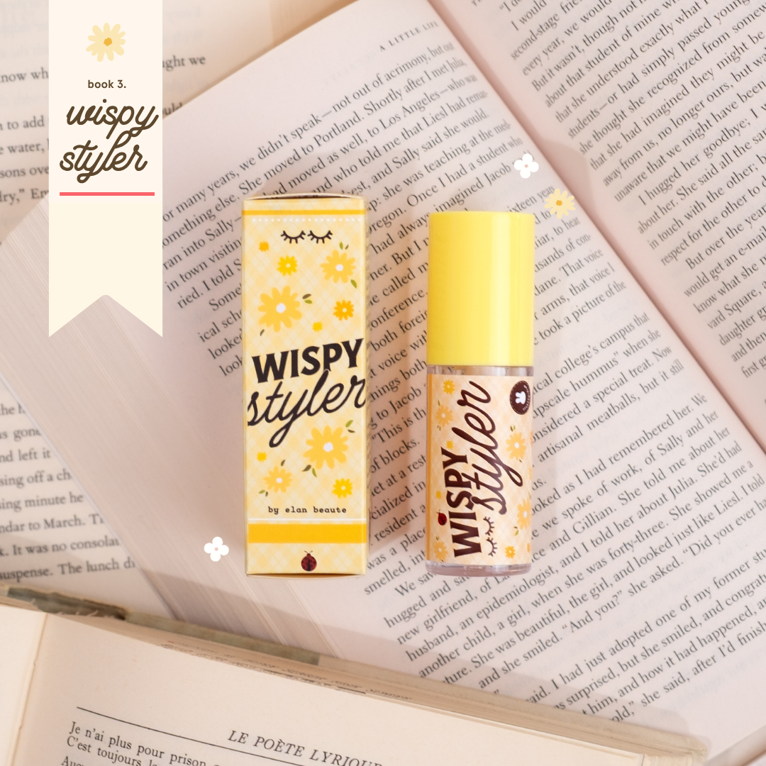 Wispy Styler lash product with yellow floral packaging, displayed on top of open book pages with small flower accents.