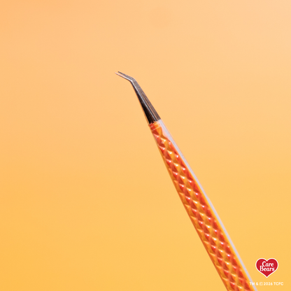 Élan Beauté x Care Bears orange volume tweezer featuring a textured grip and angled tip, shown against a purple background.