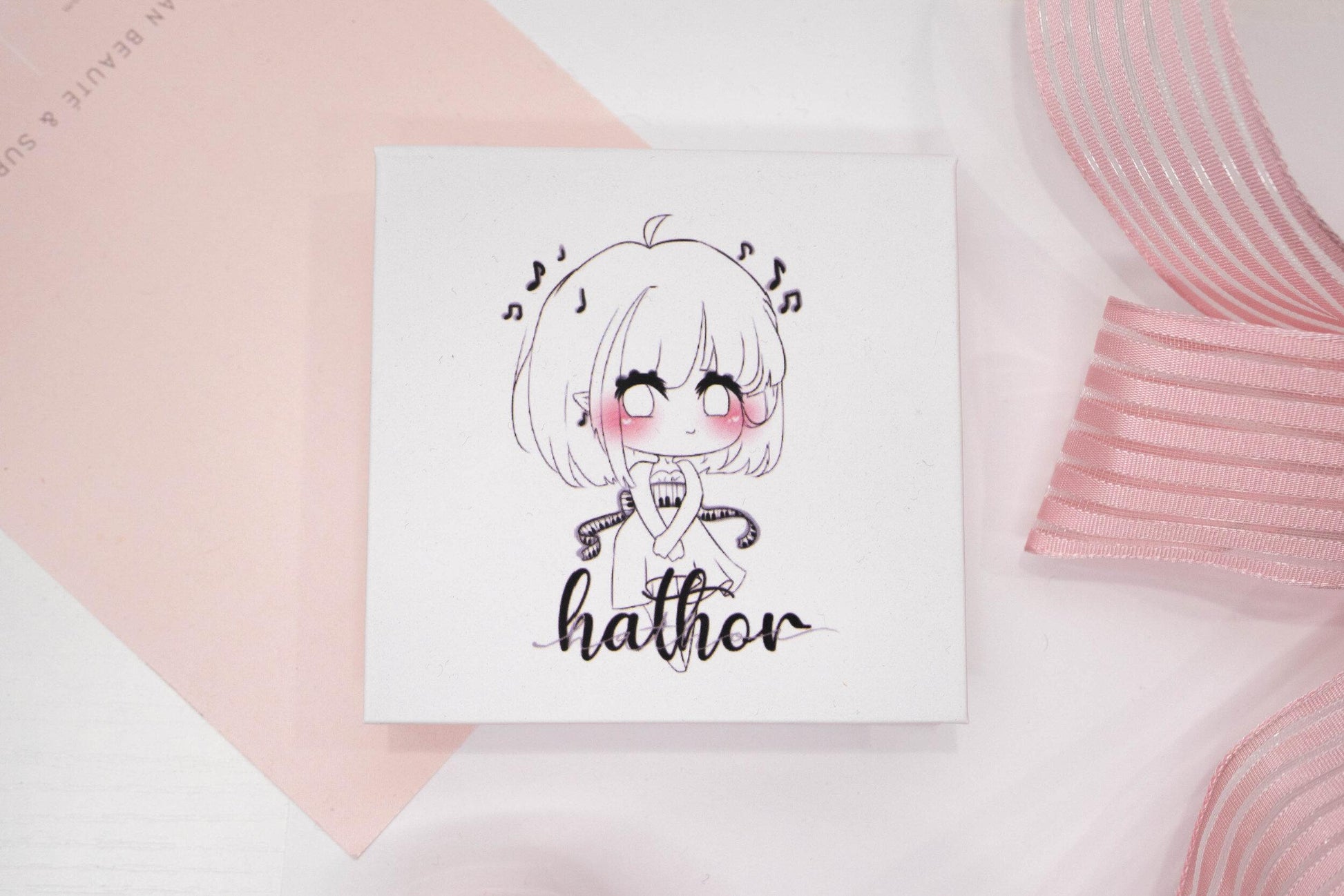 Hathor false eyelash box featuring an illustrated character on a white and pale pink background.