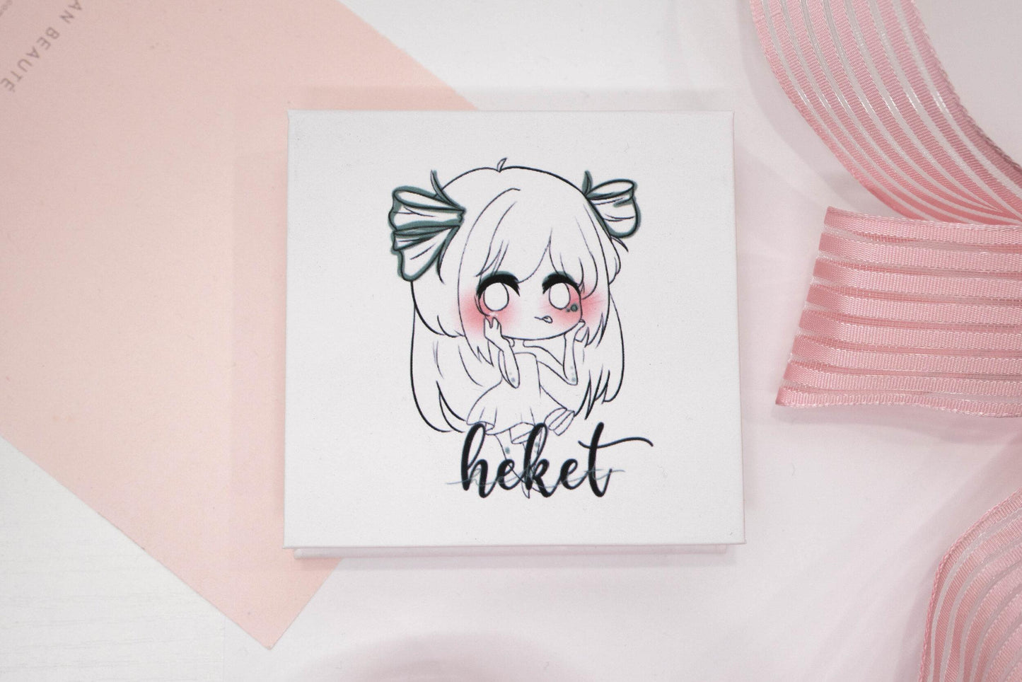 Heket false eyelash box featuring an illustrated character on a white and pale pink background.