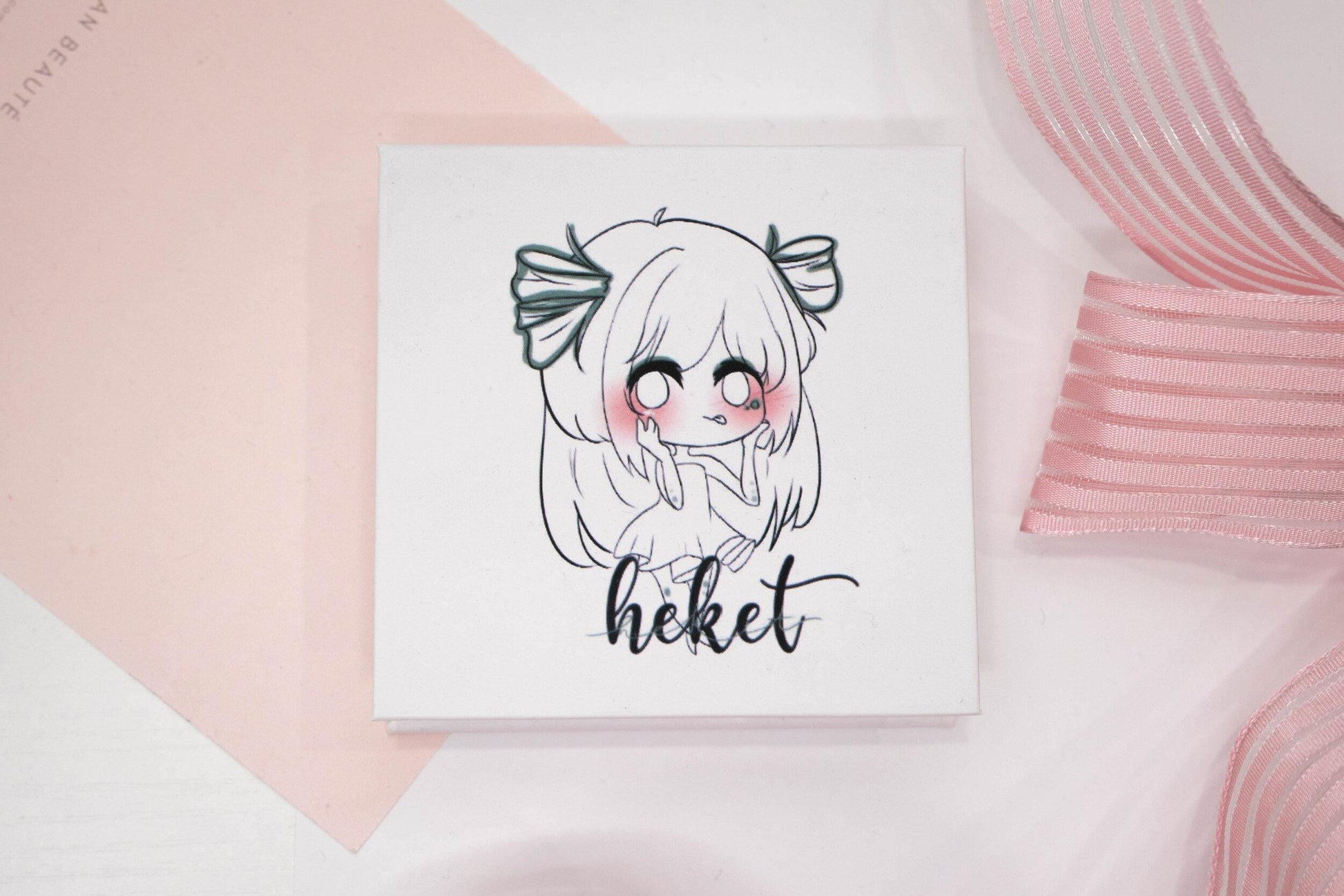 Heket false eyelash box featuring an illustrated character on a white and pale pink background.