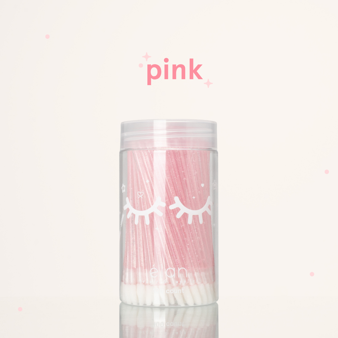 Élan Beauté pink glitter lash applicator brushes in a clear 100-count container with white eyelash graphics, displayed on a soft cream background with pink accents.