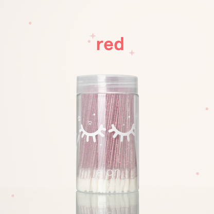 Élan Beauté red glitter lash applicator brushes in a clear 100-count container with white eyelash graphics, displayed on a soft cream background with red accents.