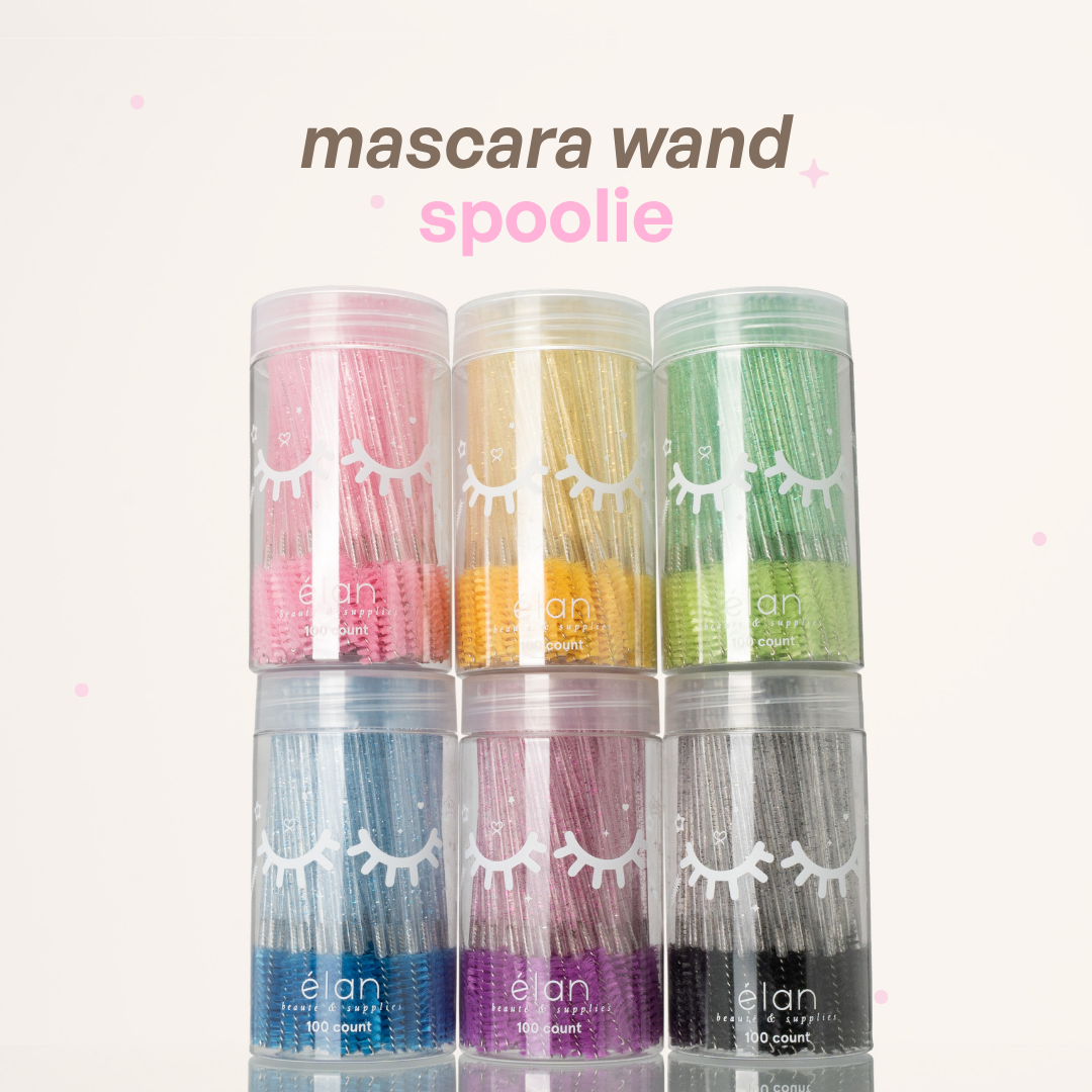 Mascara wand spoolies in clear containers, featuring glittery pink, yellow, green, blue, purple, and black handles with spoolie tips.