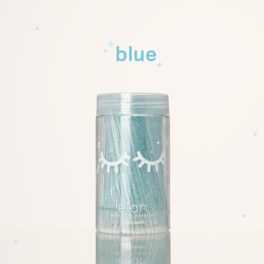 Élan Beauté blue glitter microbrush applicator brushes in a clear 100-count container with white eyelash graphics, displayed on a soft cream background with blue accents.