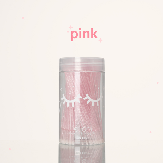 Élan Beauté pink glitter microbrush applicator brushes in a clear 100-count container with white eyelash graphics, displayed on a soft cream background with pink accents.