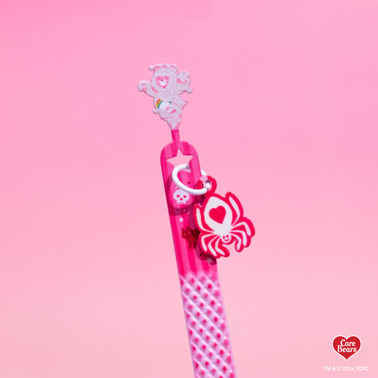 Élan Beauté x Care Bears pink Halloween lash tweezer featuring a textured grip, Care Bear topper, and dangling skull charm against a light pink background.
