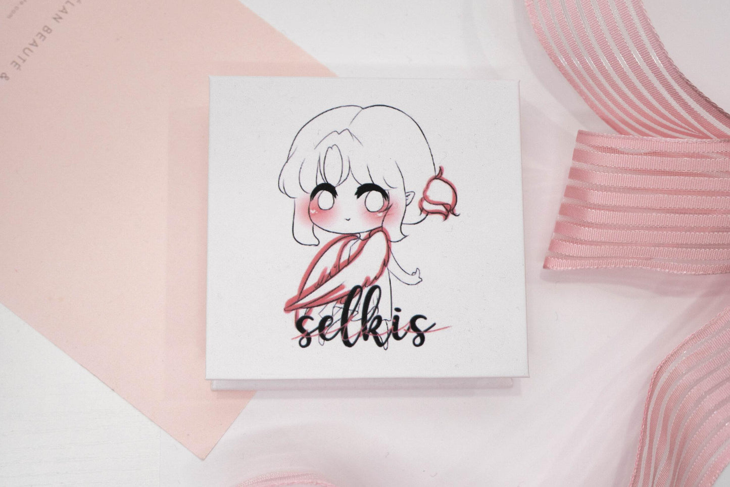 Selkis false eyelash box featuring an illustrated character on a white and pale pink background.