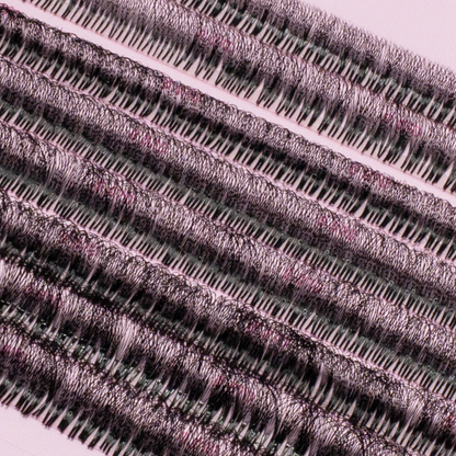 Close-up of rows of premade lash fans arranged on a pink lash tray, showing dense, evenly spaced black lash clusters.