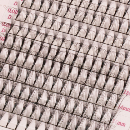 Close-up of premade volume lash fans arranged in rows on a pink tray, showing fine black fibers and pointed bases.