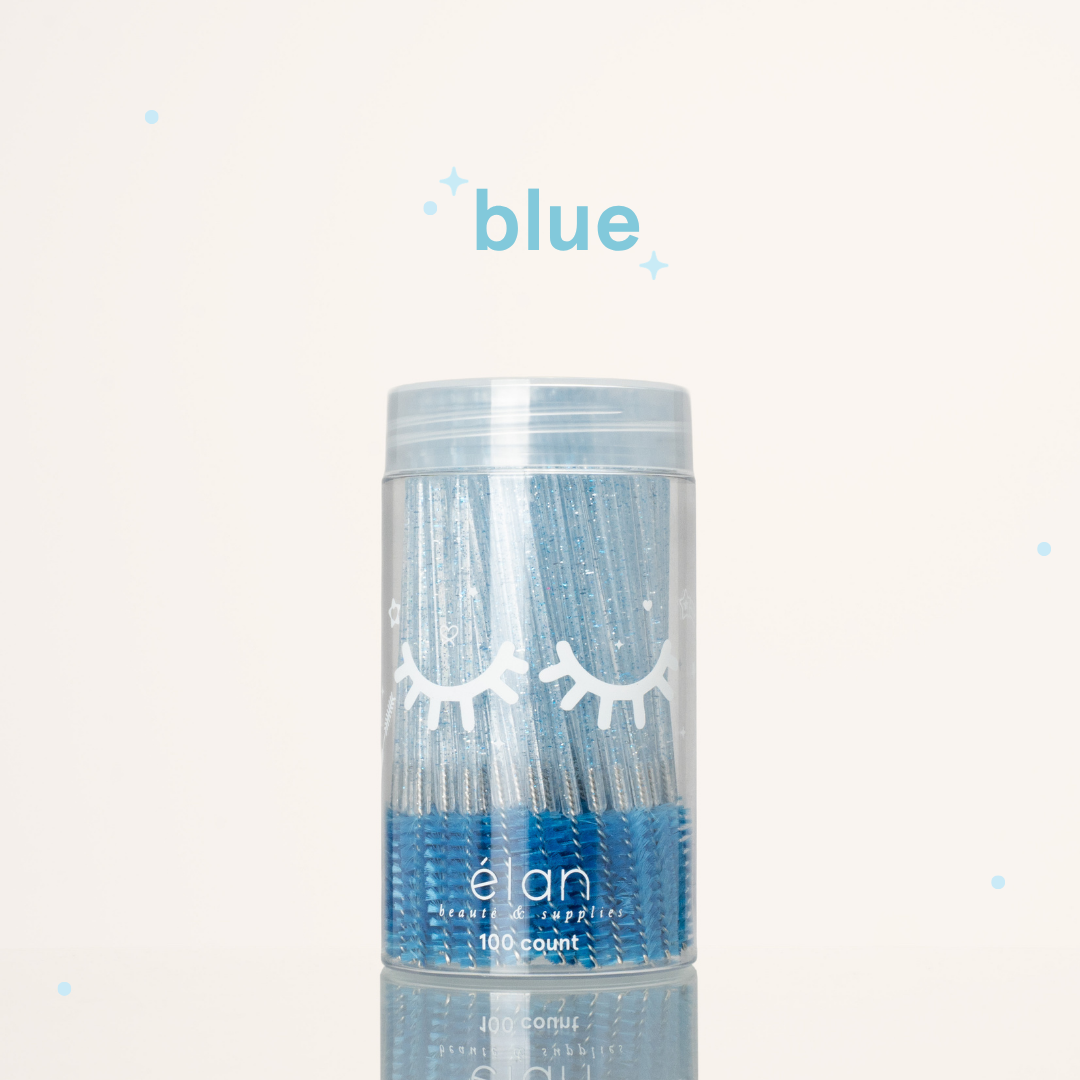 Élan Beauté blue glitter spoolies in a clear 100-count container with white eyelash graphics, displayed on a soft cream background with blue accents.
