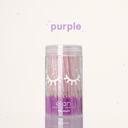 Élan Beauté purple glitter spoolies in a clear 100-count container with white eyelash graphics, displayed on a soft cream background with purple accents.