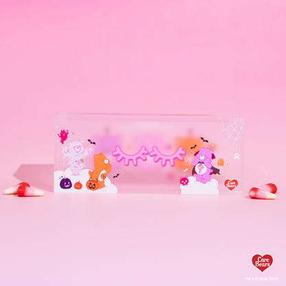Élan Beauté x Care Bears Halloween magnetic tweezer case featuring pink, orange, and purple Care Bears character artwork with bats, pumpkins, spiderweb details, and candy corn accents.