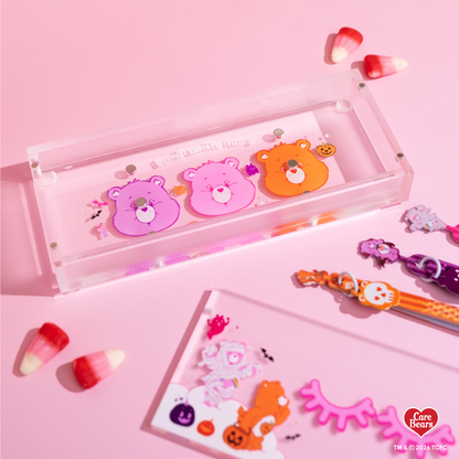 Élan Beauté x Care Bears Halloween magnetic tweezer case featuring pink, orange, and purple Care Bears character artwork with bats, pumpkins, spiderweb details, and candy corn accents.